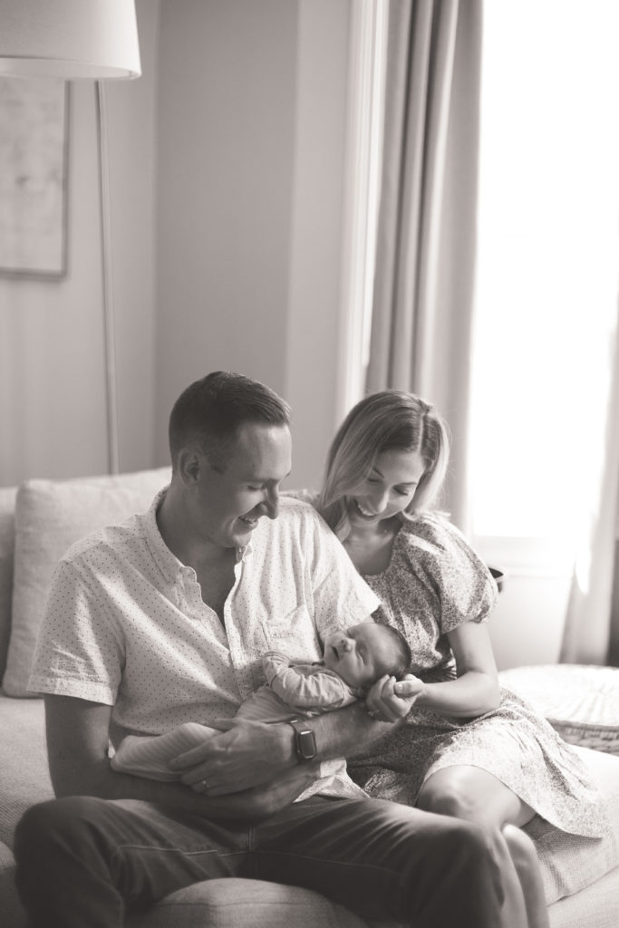 mom and dad with newborn on couch black and white newborn photography cincinnati